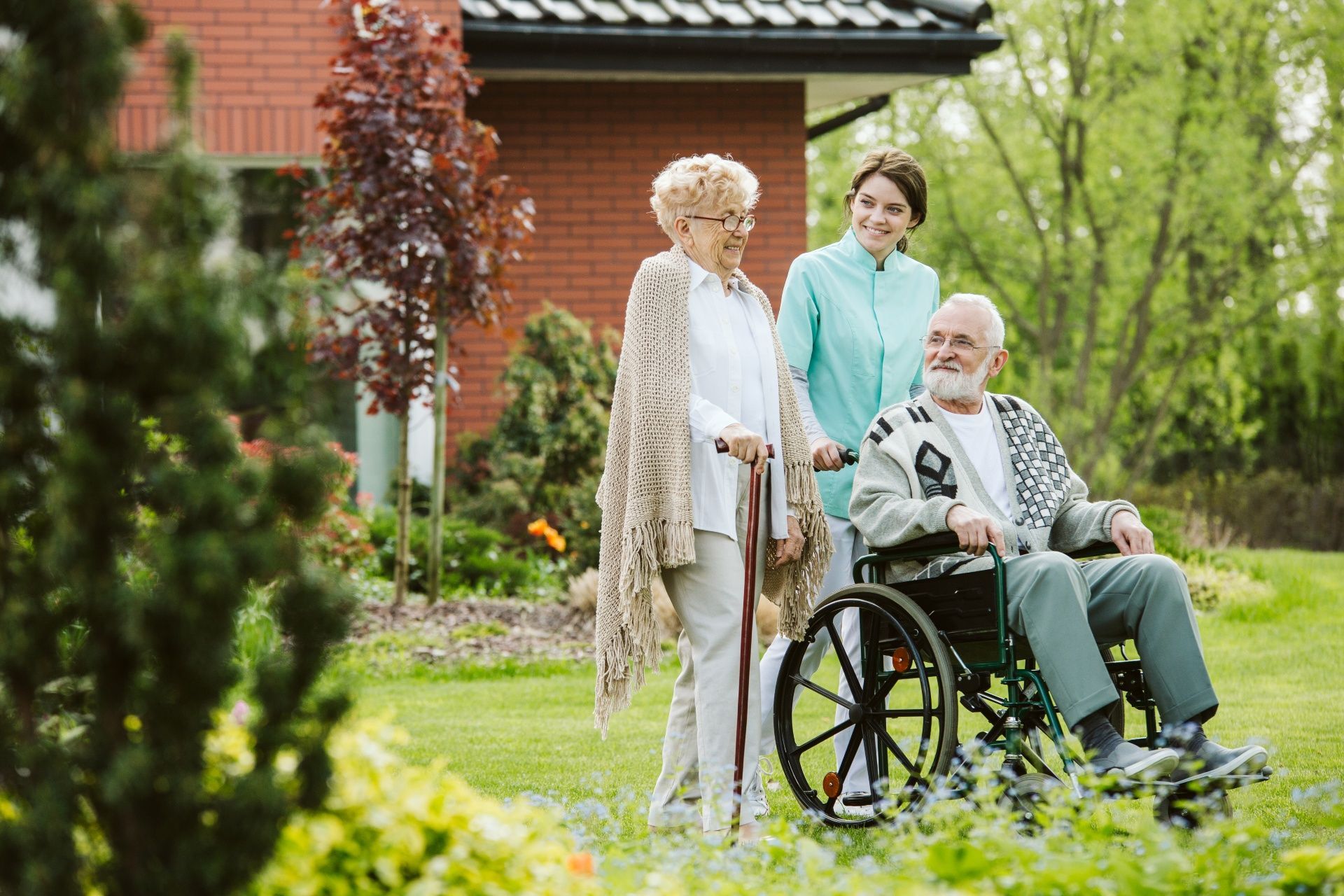 A nurse with two old person outside of the center