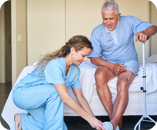 A nurse is helping an elderly man put on his shoes.