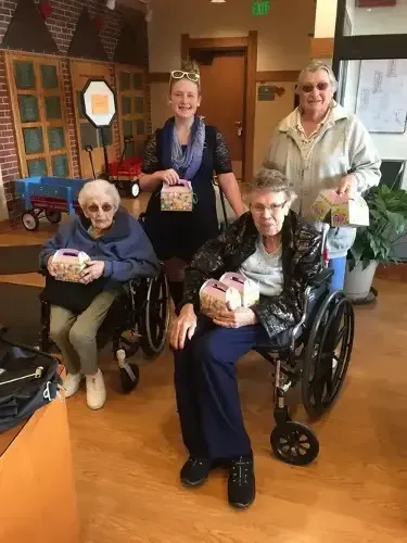 A group of elderly women in wheelchairs are posing for a picture.