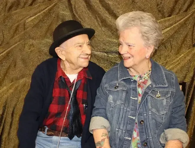 A man and a woman are standing next to each other and smiling.