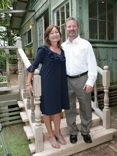 A man and a woman are posing for a picture on the steps of a house.