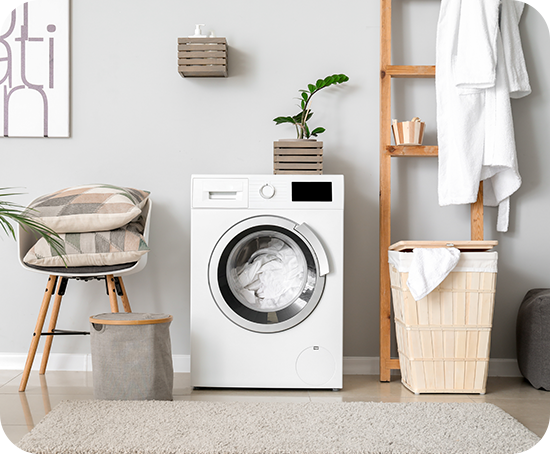 A washing machine is sitting in a laundry room next to a chair.