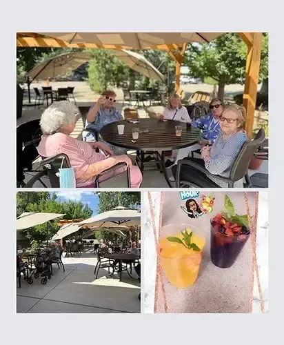 A group of elderly people are sitting at tables under umbrellas.