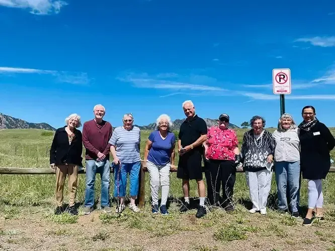 A group of people are standing in a field in front of a no parking sign.