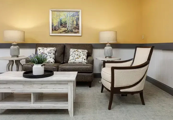 A living room with a couch , chair , coffee table and lamps.