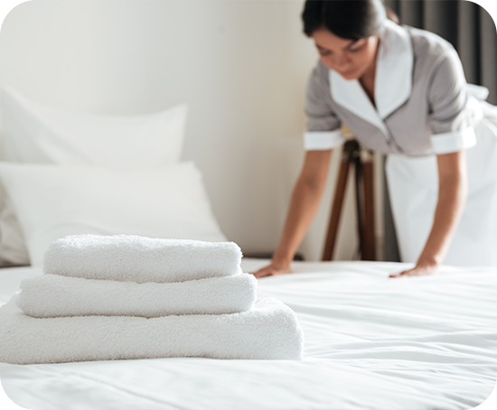 A maid is making a bed in a hotel room