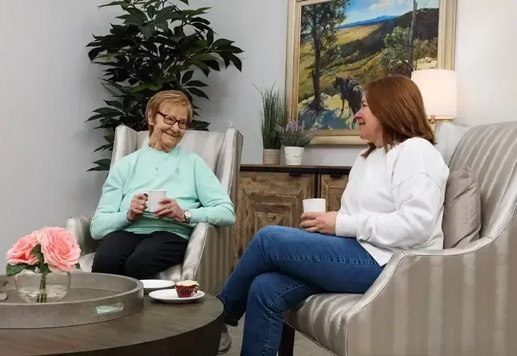 Two women are sitting on a couch talking to each other.