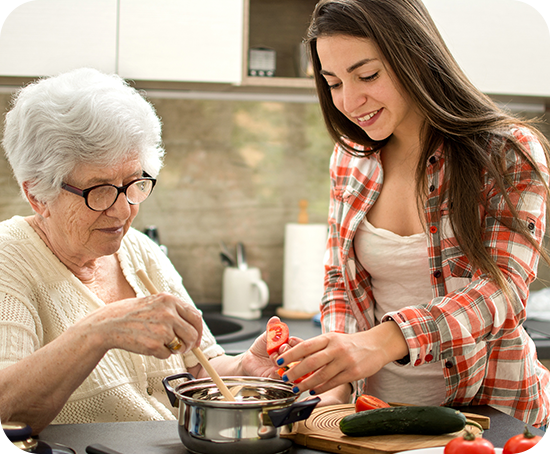 A young woman is helping an older woman cook in a kitchen.