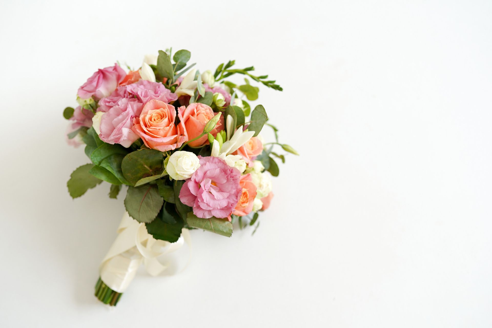 Bouquet of pink and peach roses, tied with ivory ribbon.