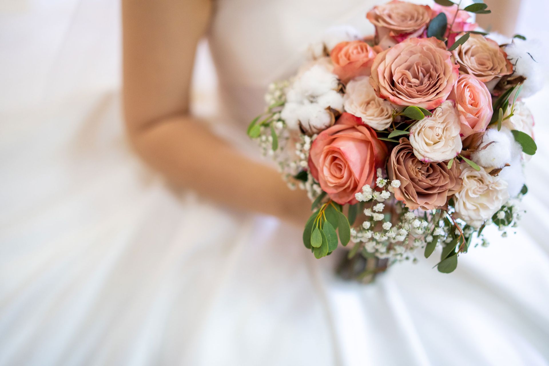 Bride holding a bouquet of peach and cream roses.