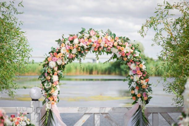 Floral wedding arch overlooking a lake, with pink and white flowers.