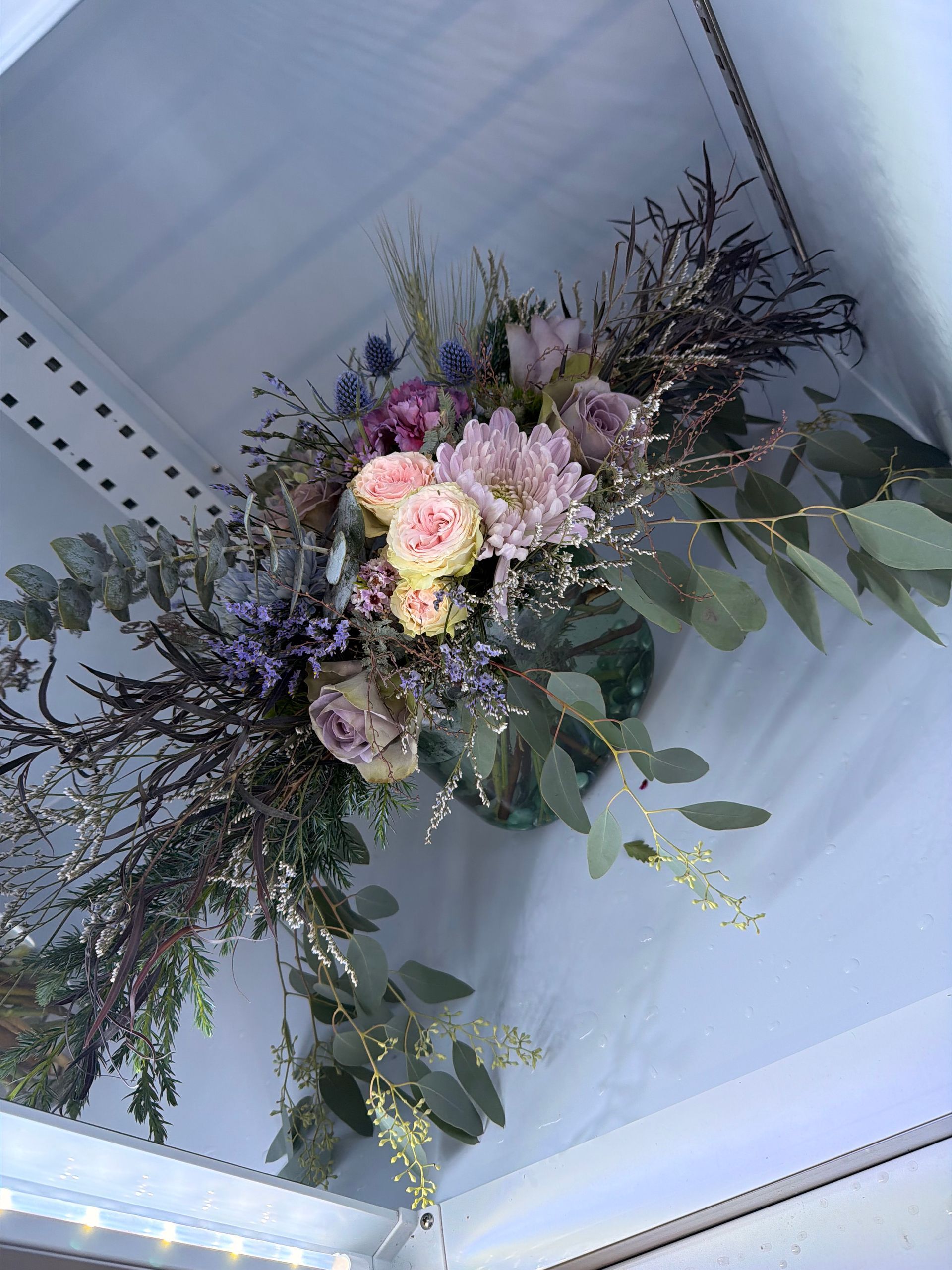 Bouquet of pink roses and green chrysanthemums in a dark vase.