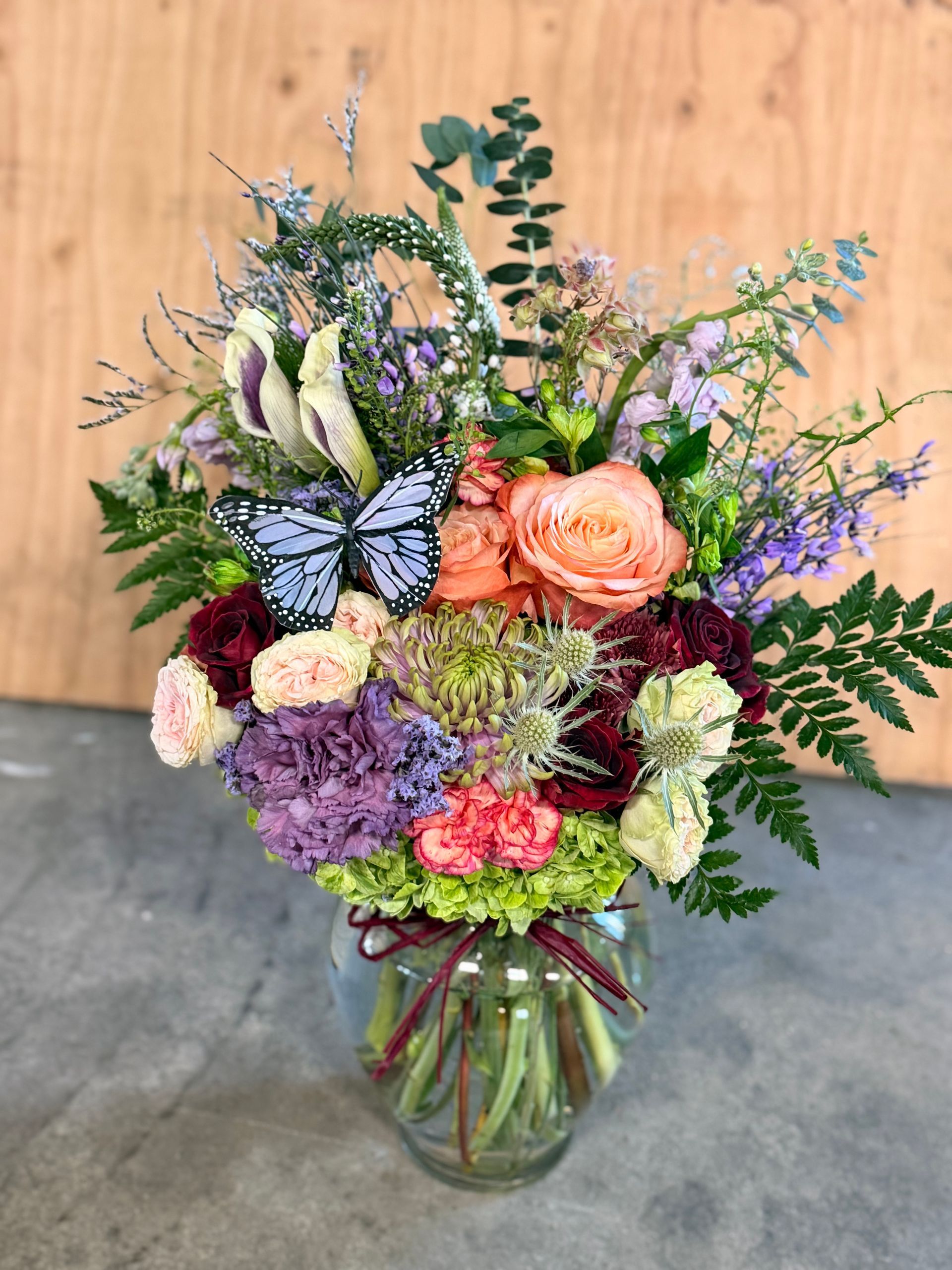 A vibrant floral arrangement in a vase on a wooden surface.