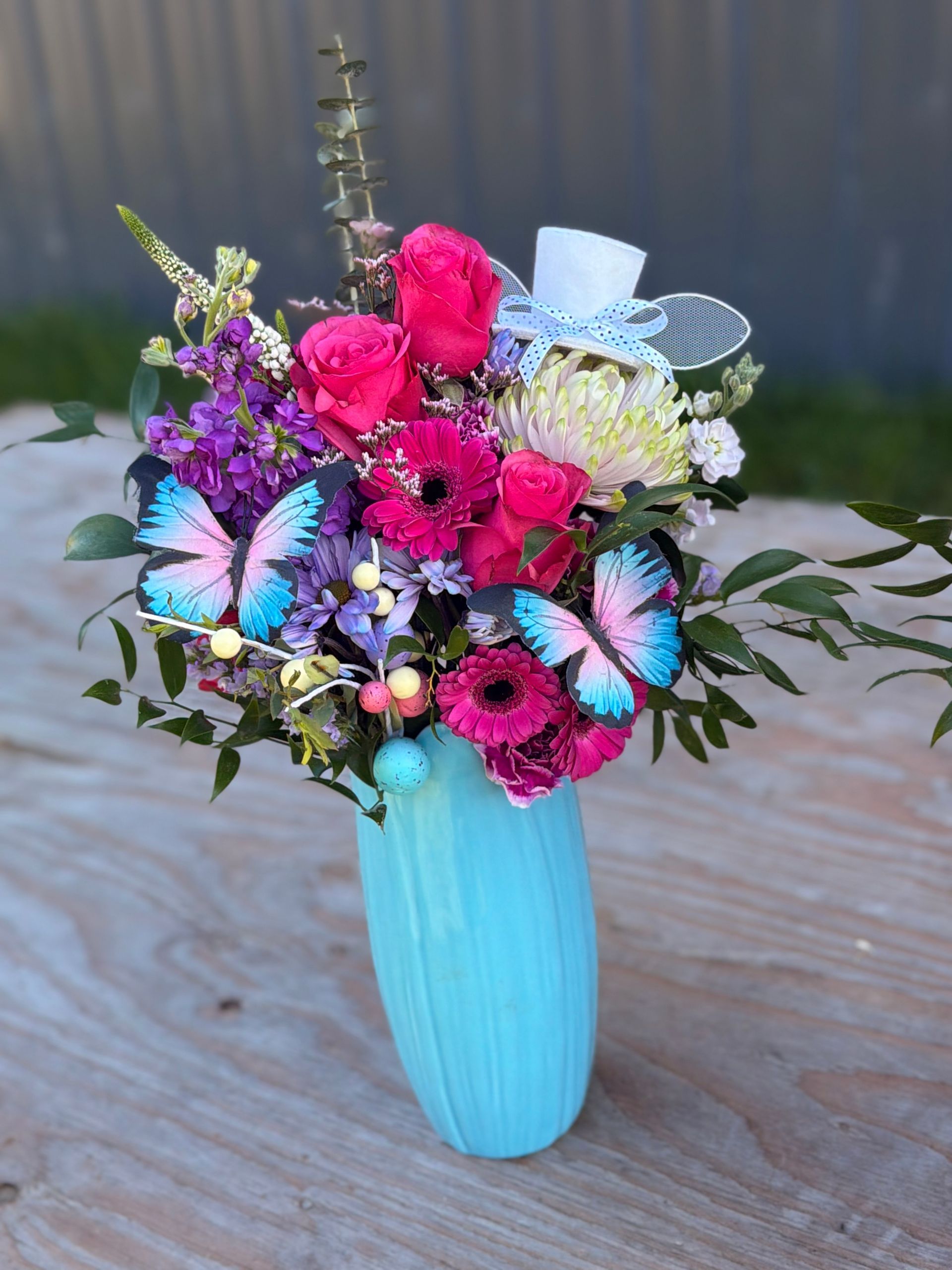 A vibrant floral arrangement in a vase on a wooden surface.