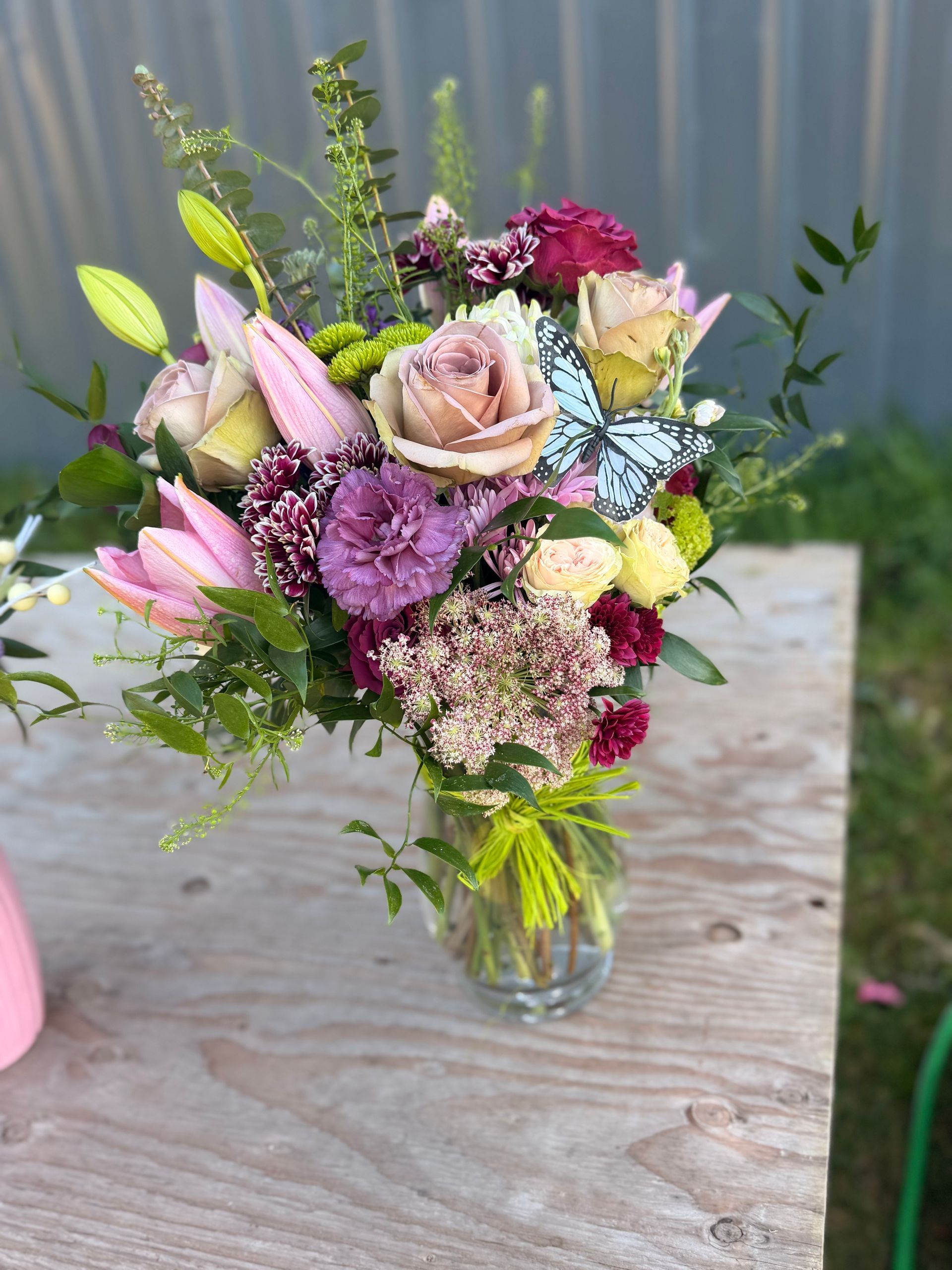 Bouquet of pink and purple flowers rests on concrete blocks in an outdoor setting.