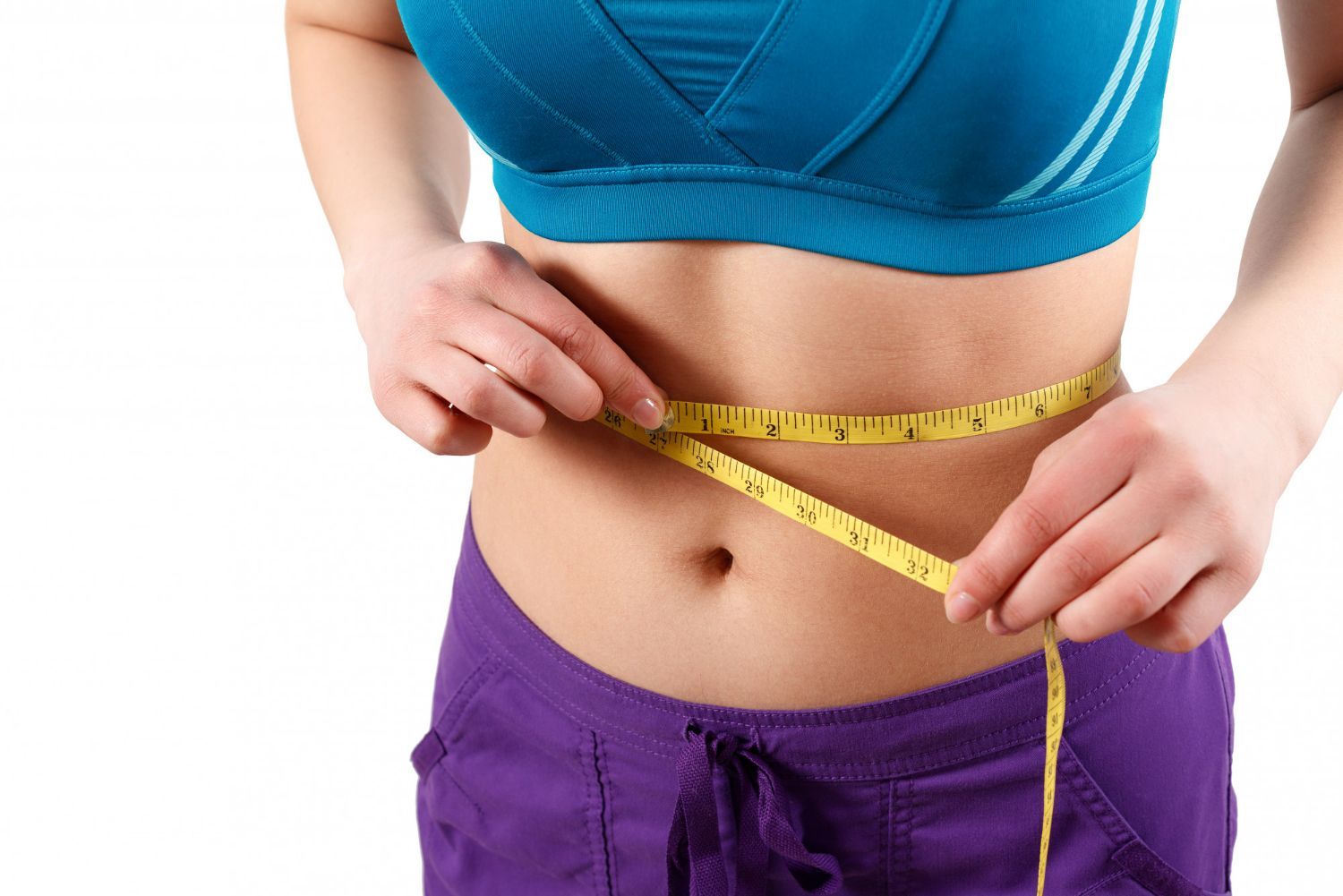 A woman is measuring her waist with a tape measure