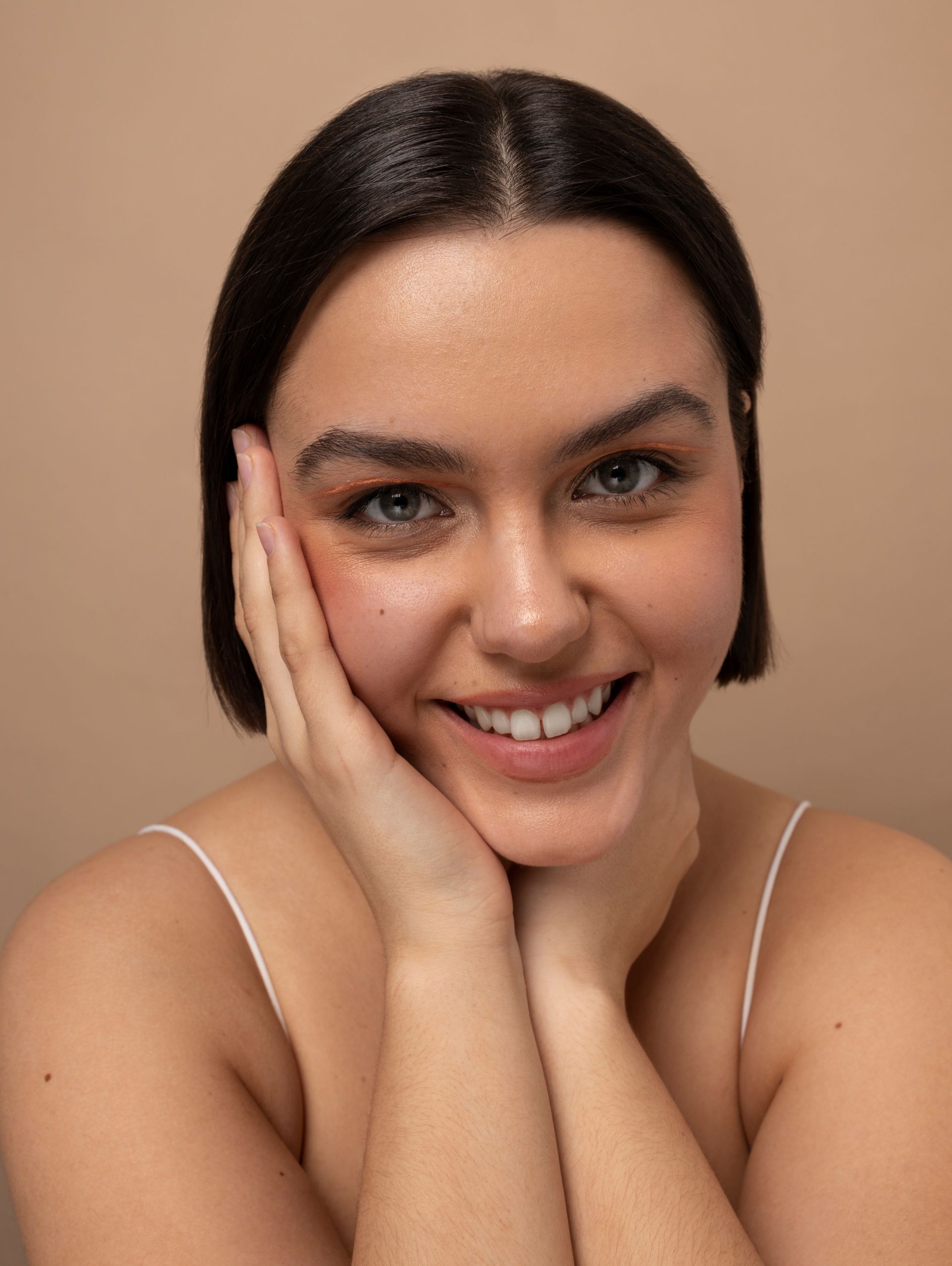 A woman is smiling with her hand on her face.