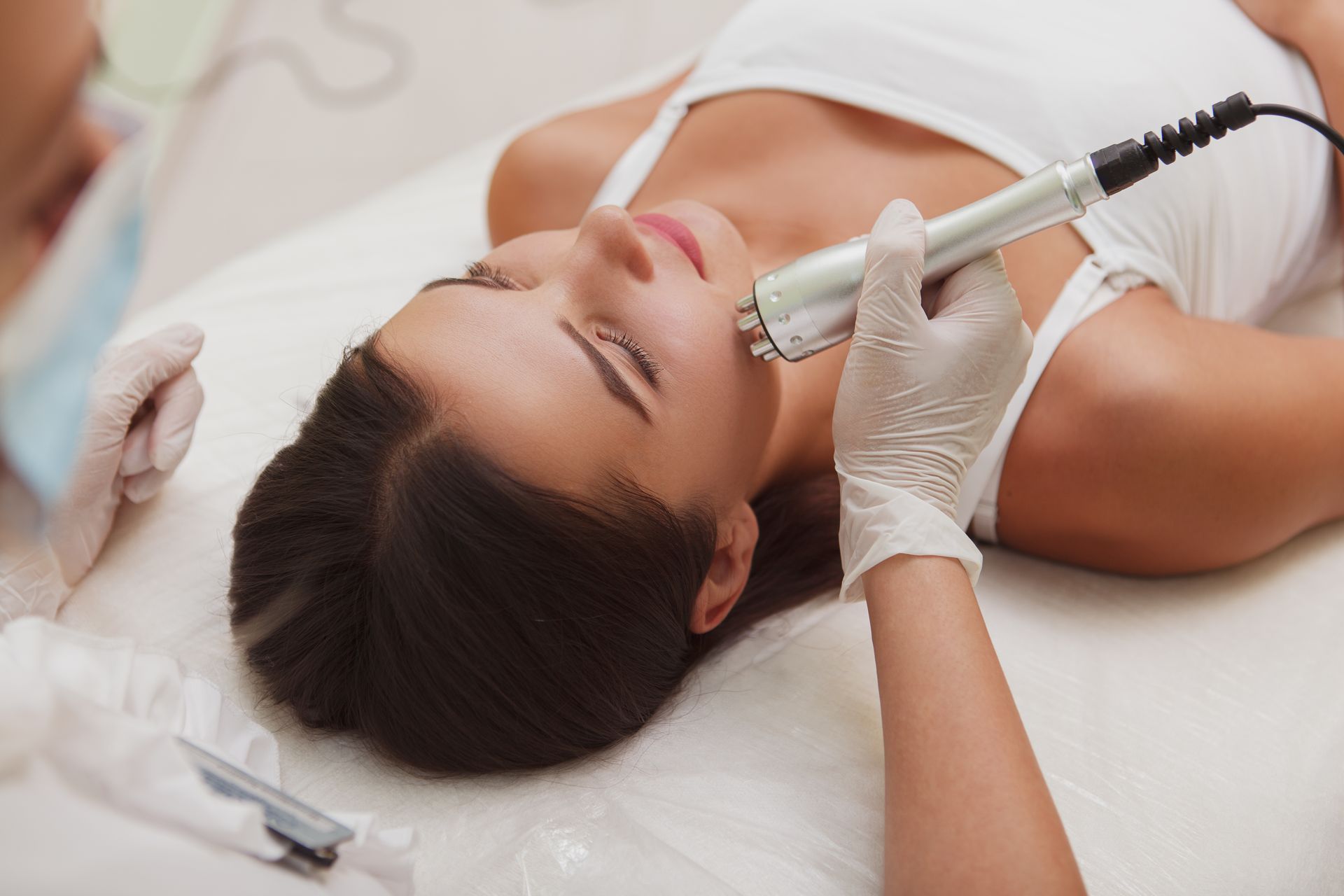 A woman is laying on a bed getting a facial treatment.