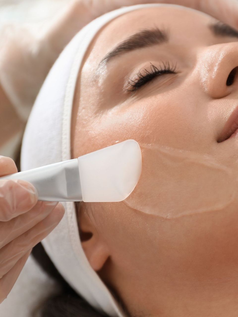 A woman is getting a facial treatment with a brush.