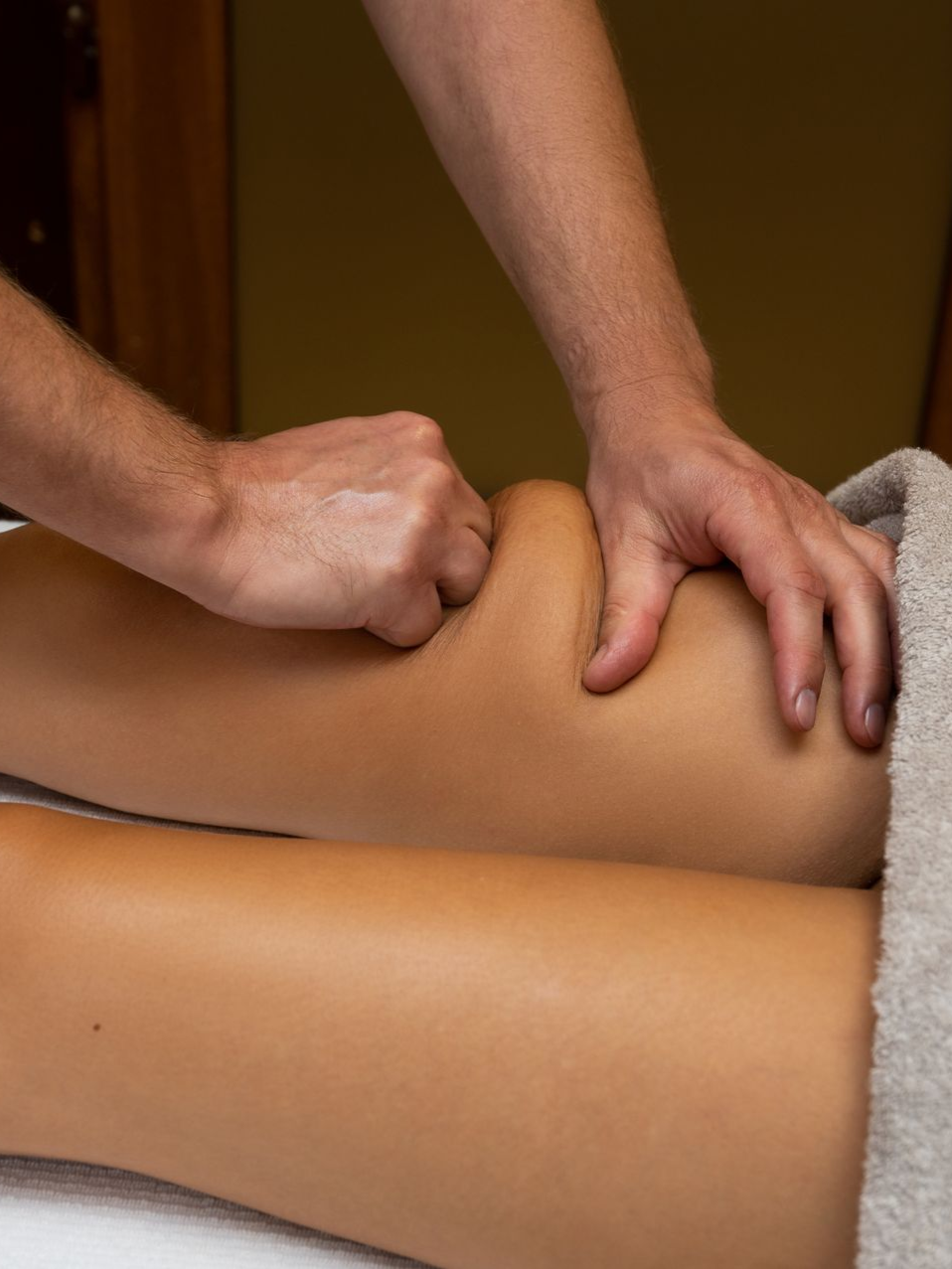 Person's leg being massaged; therapist's hands kneading the calf muscle.