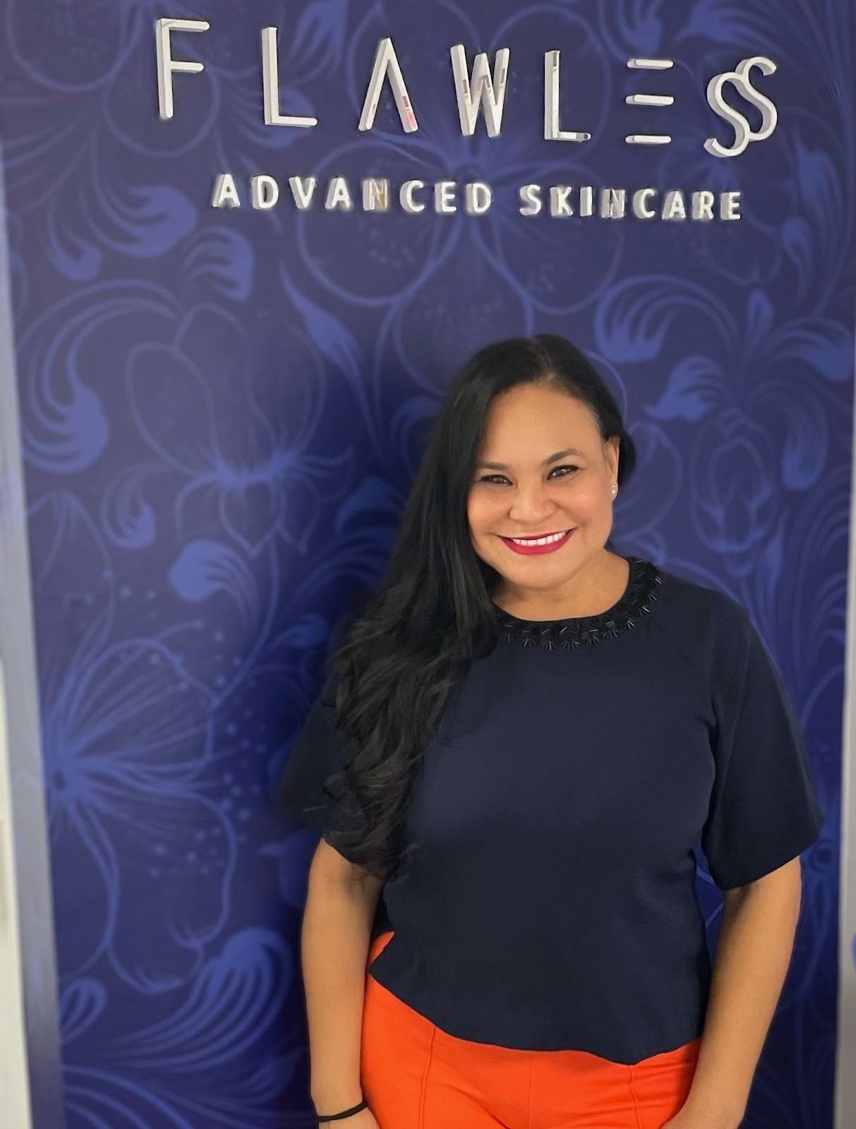 A woman stands in front of a sign that says flawless advanced skincare