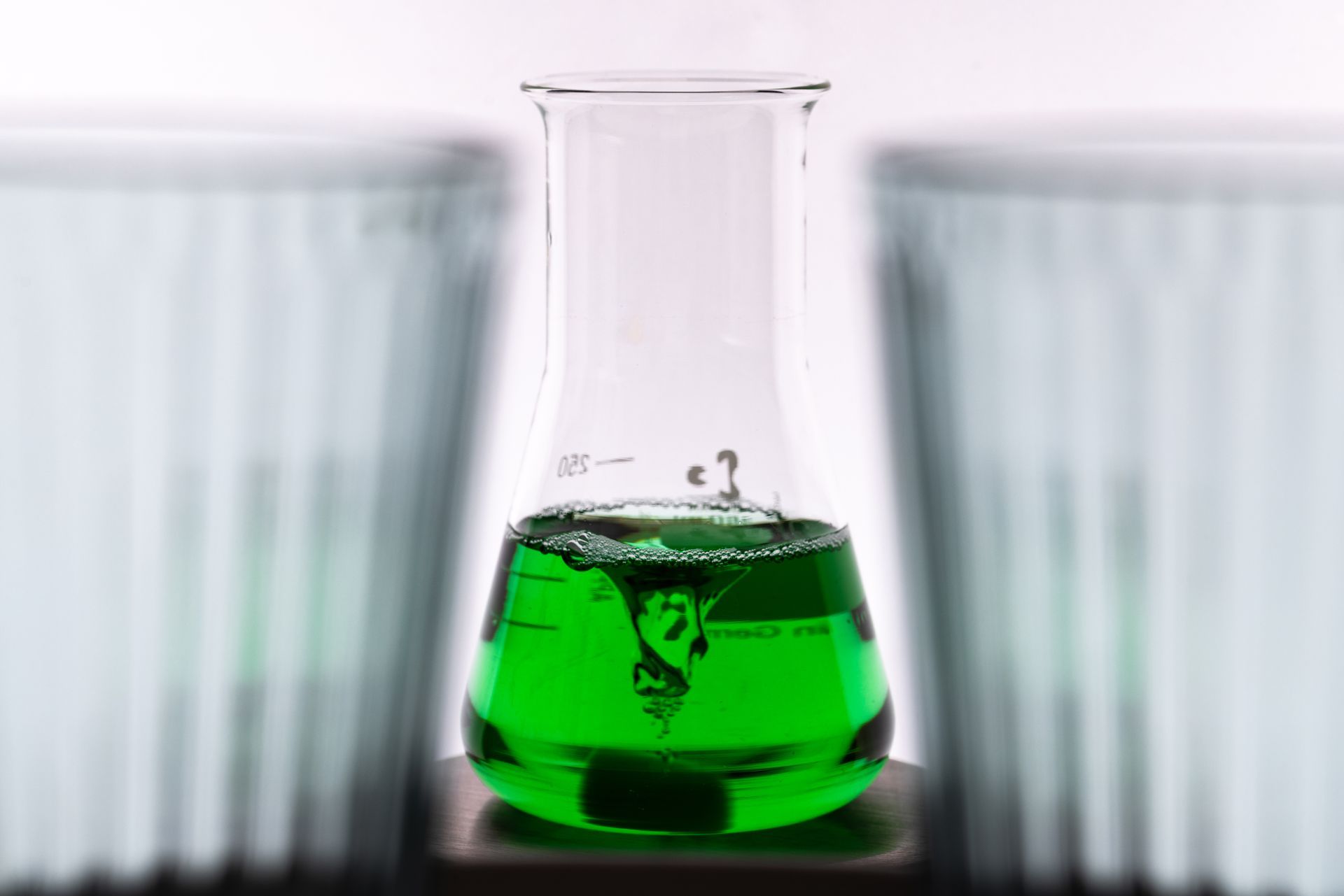 Green liquid swirling in a lab flask.