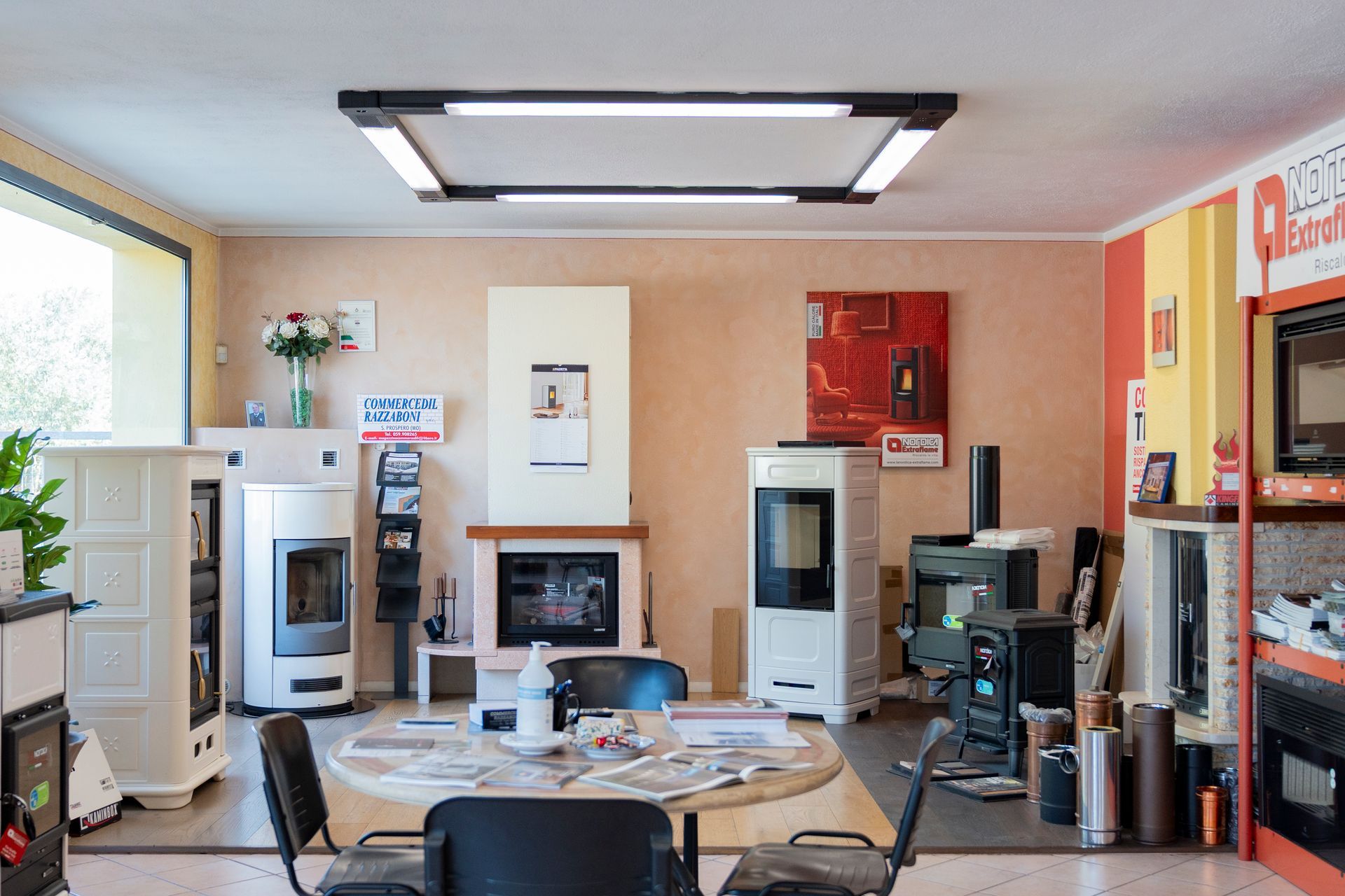 Soggiorno moderno con camino, TV, tavolo rotondo e grande lampadario a soffitto in un interno luminoso e ordinato.