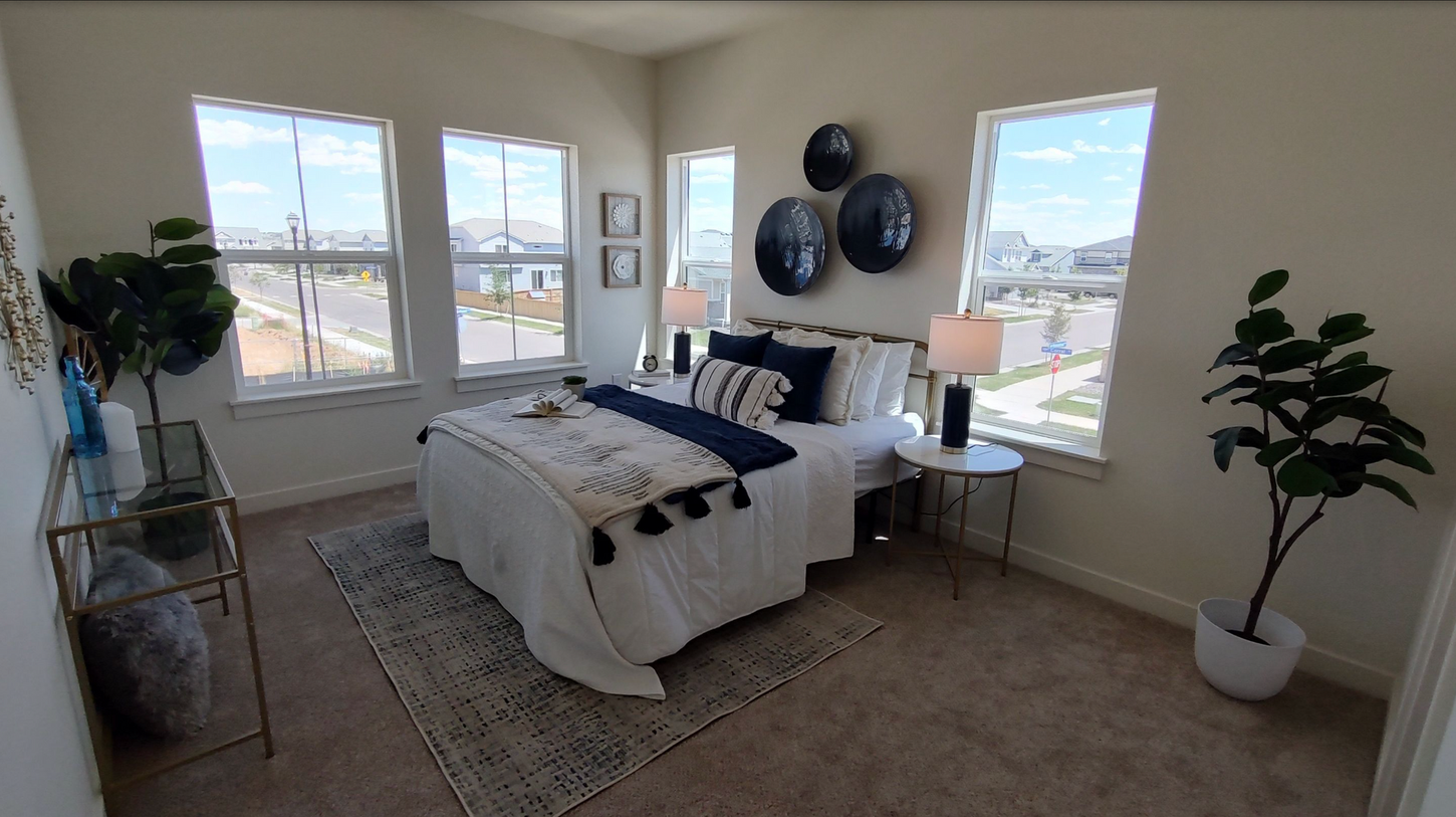 A bedroom with a bed , lamps , and a plant.