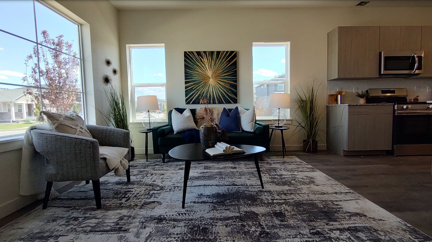 A living room with a couch , chairs , a coffee table and a rug.