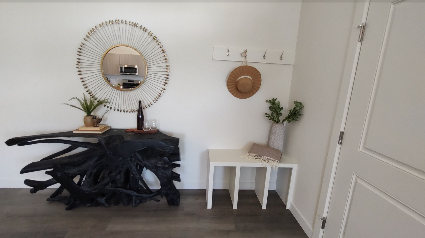 A hallway with a black table and a mirror on the wall.
