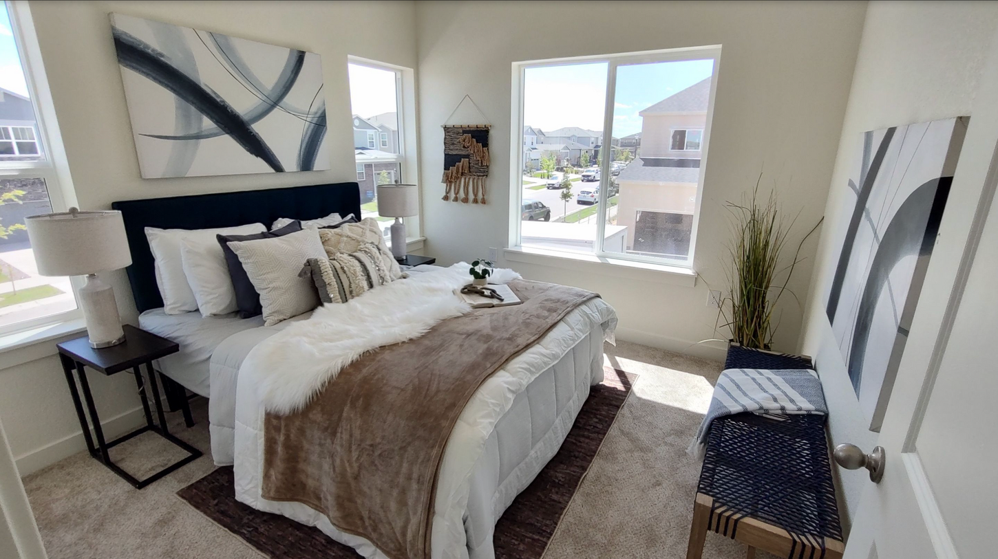 A bedroom with a king size bed , two windows and a bench.