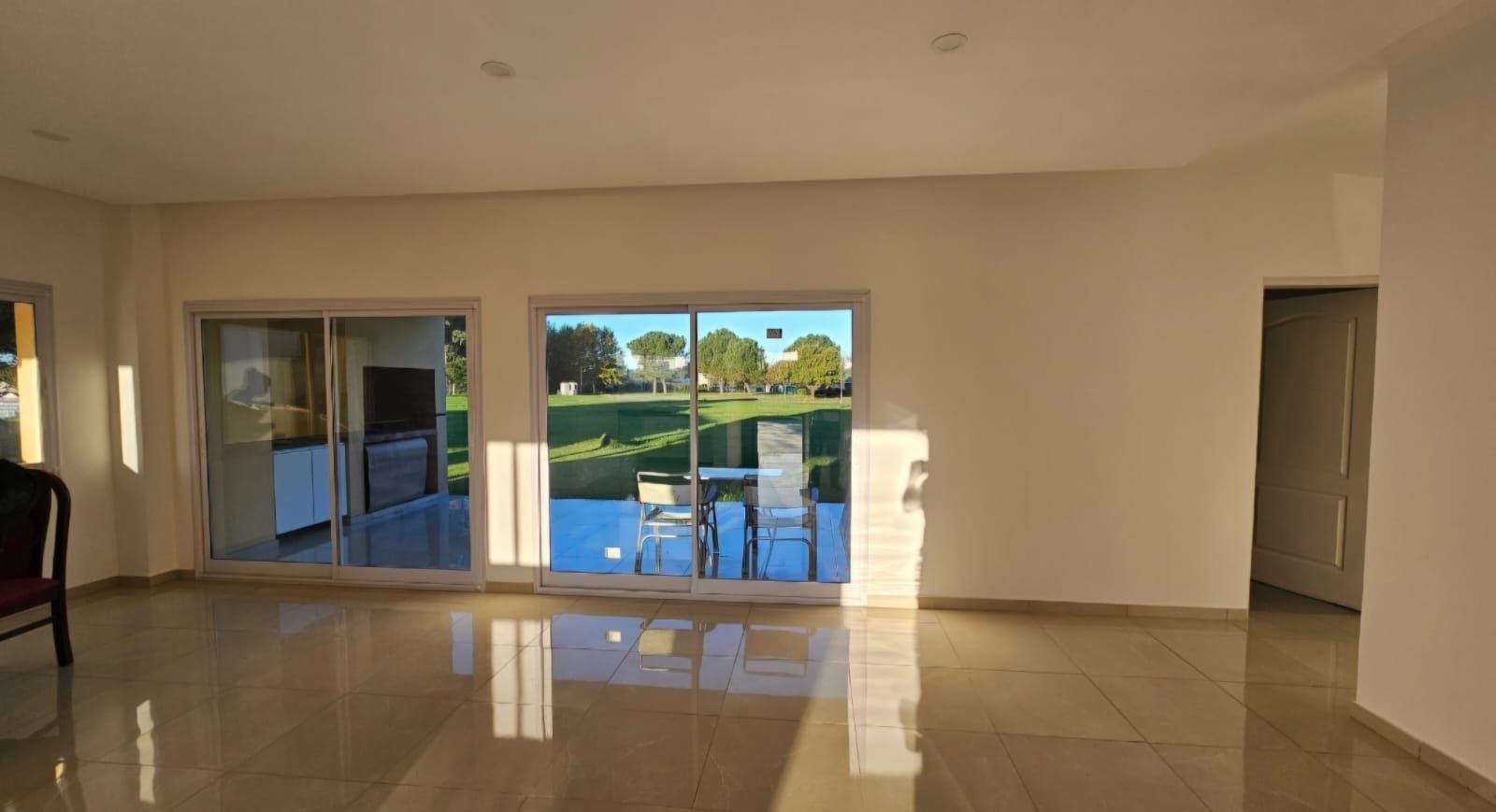 Sala de estar vacía con suelo de baldosas y grandes puertas correderas de cristal