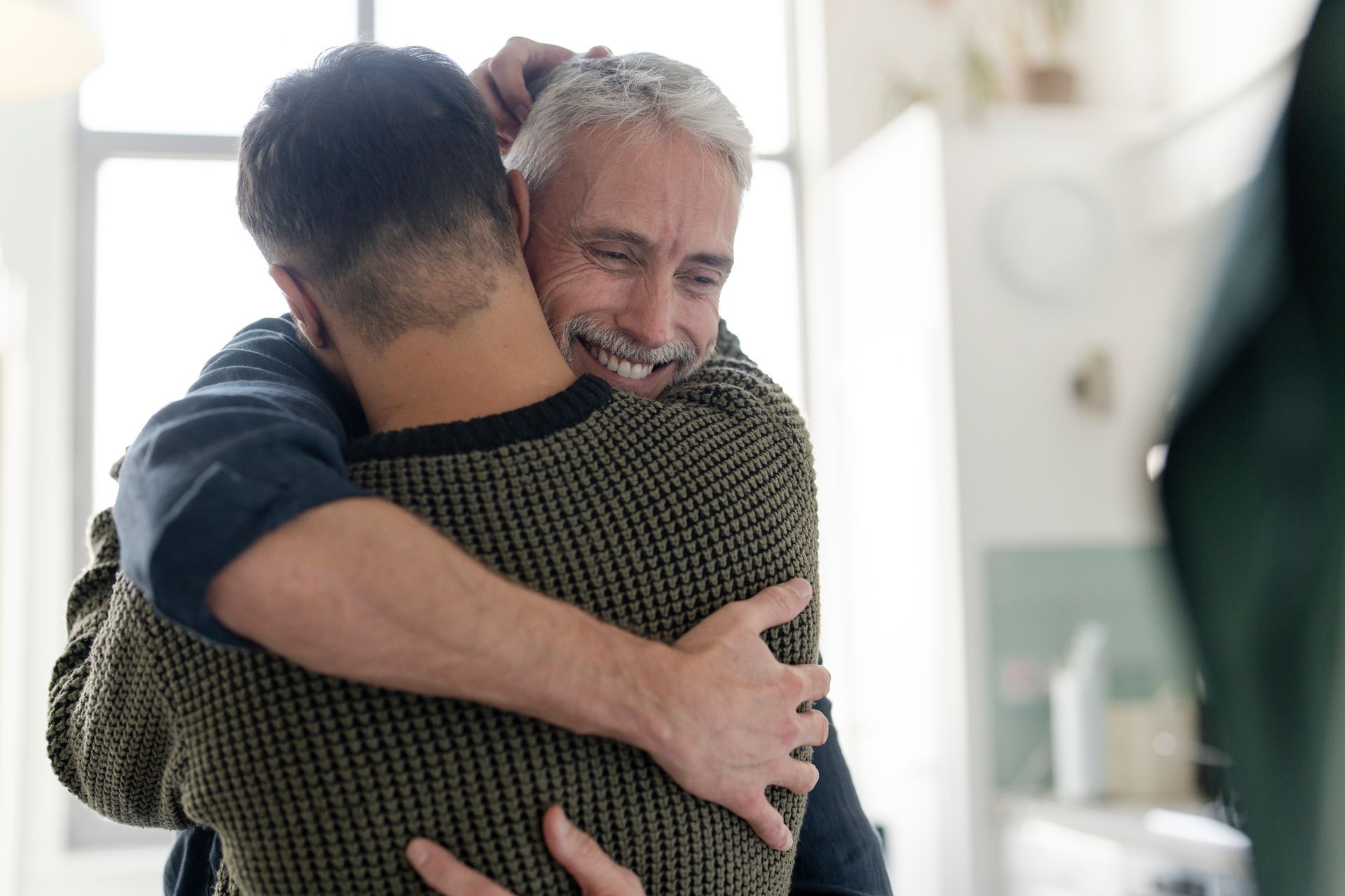 Male couple hugging at home.