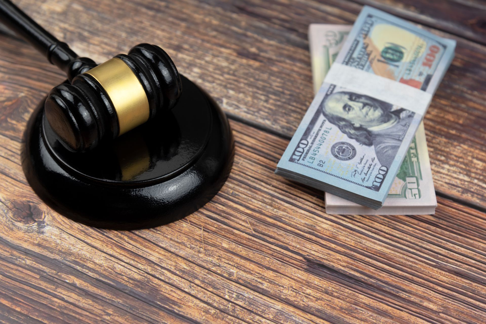 A judge's gavel rests on a wooden table surrounded by stacks of money, symbolizing a bail bondsman.