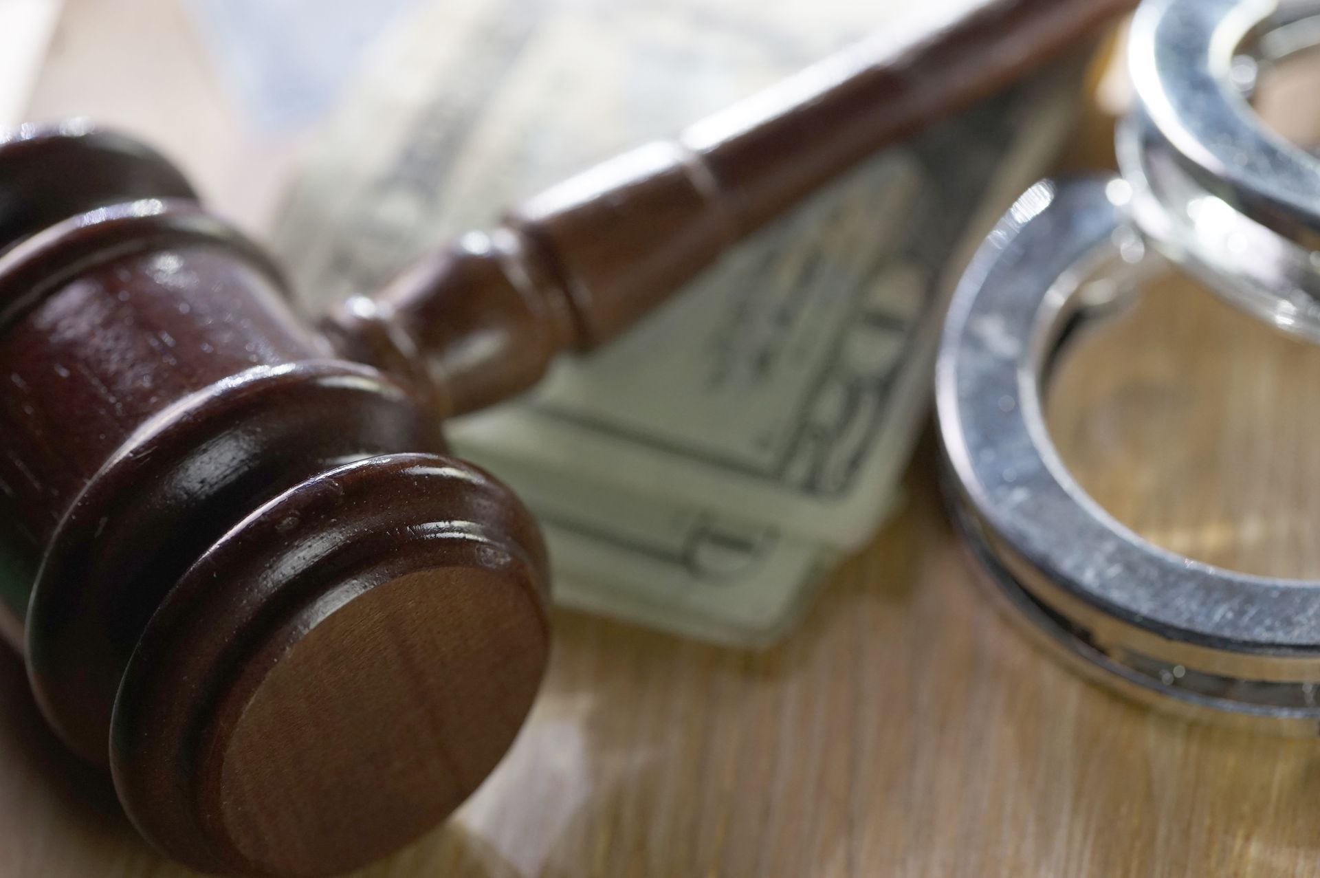 Gavel, handcuffs, and dollar bills on wood surface symbolizing justice, law, and legal enforcement.