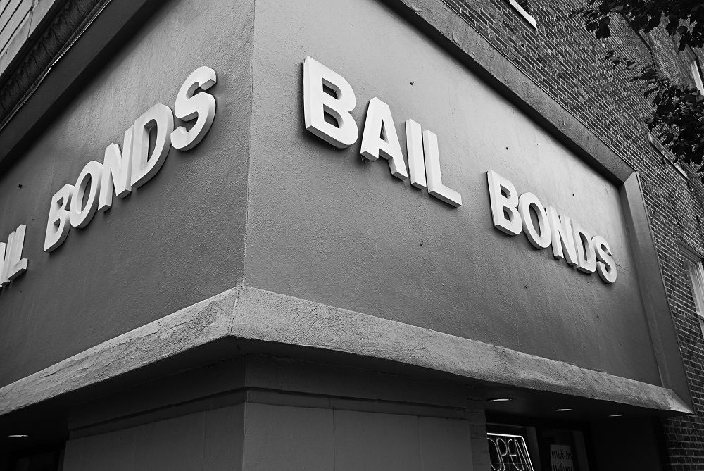 Black and white photo of corner building with large white 'Bail Bonds' sign on brick façade.