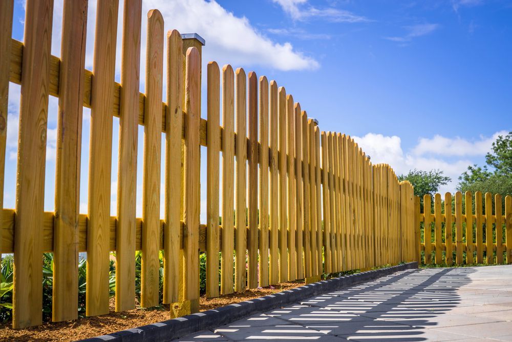 Classic light brown vertical wood picket fence.