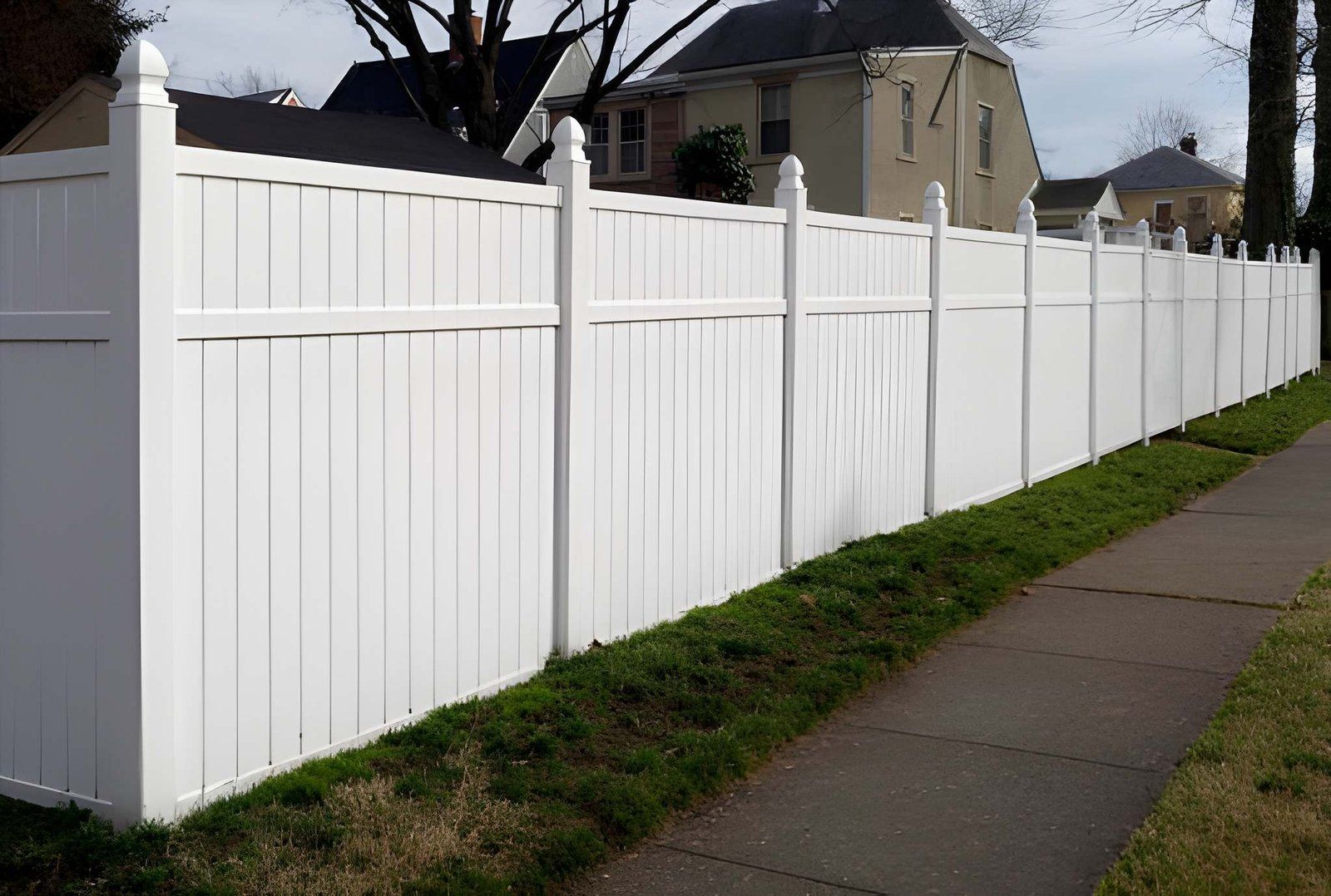 White vinyl privacy fence installation along a sidewalk.