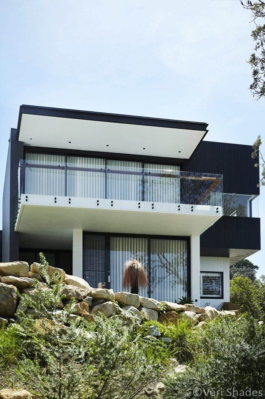 A Black and White House With a Balcony on Top of It — Abode Shutters & Blinds In Taree South, NSW