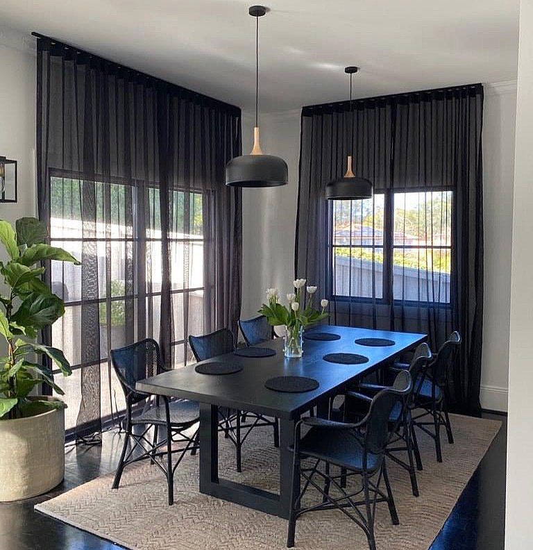 A Dining Room With a Table and Chairs and Black Curtains — Abode Shutters & Blinds In Taree South, NSW