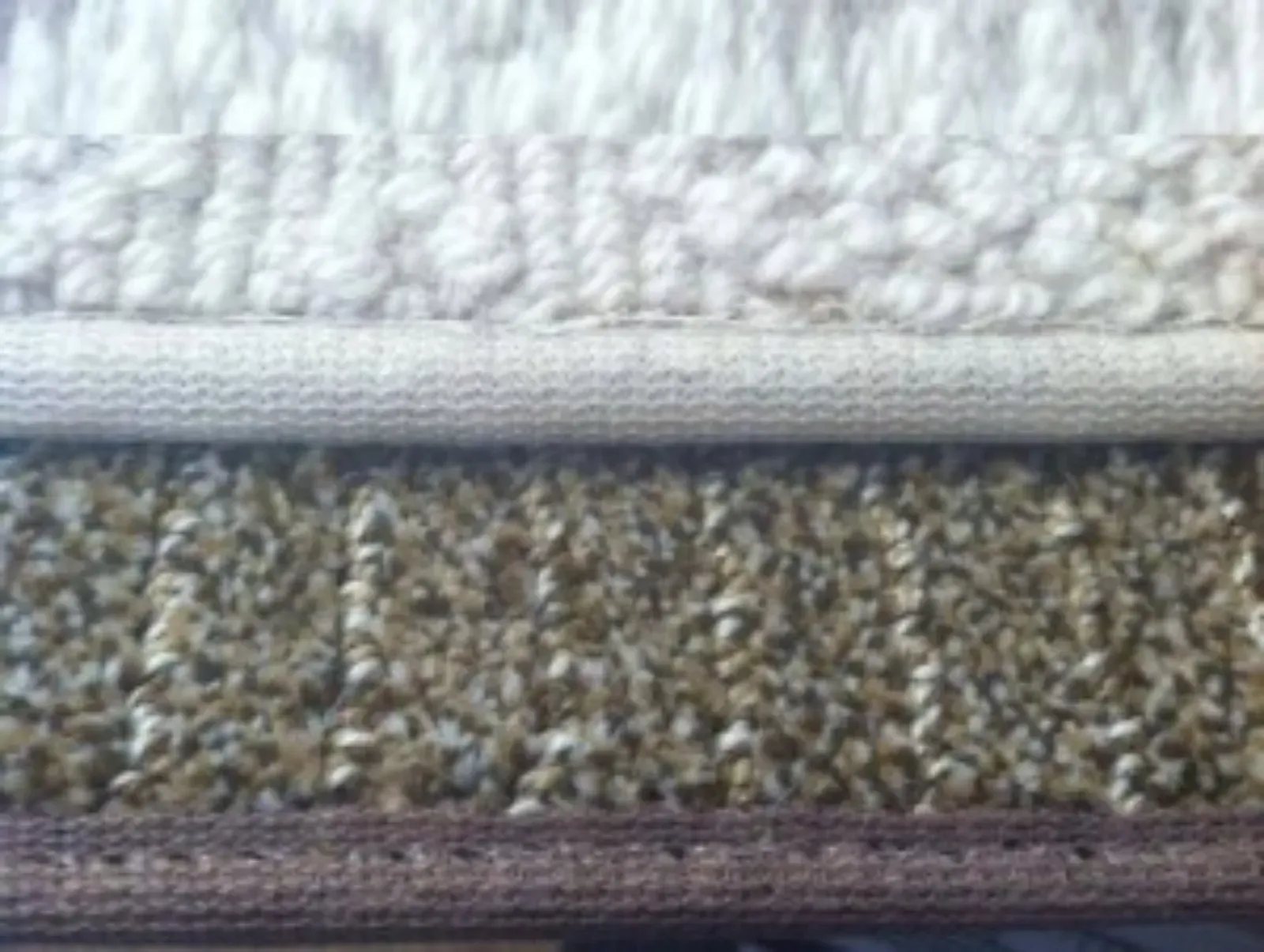 Close-up view of carpet samples in neutral colors, showing texture and edging details.