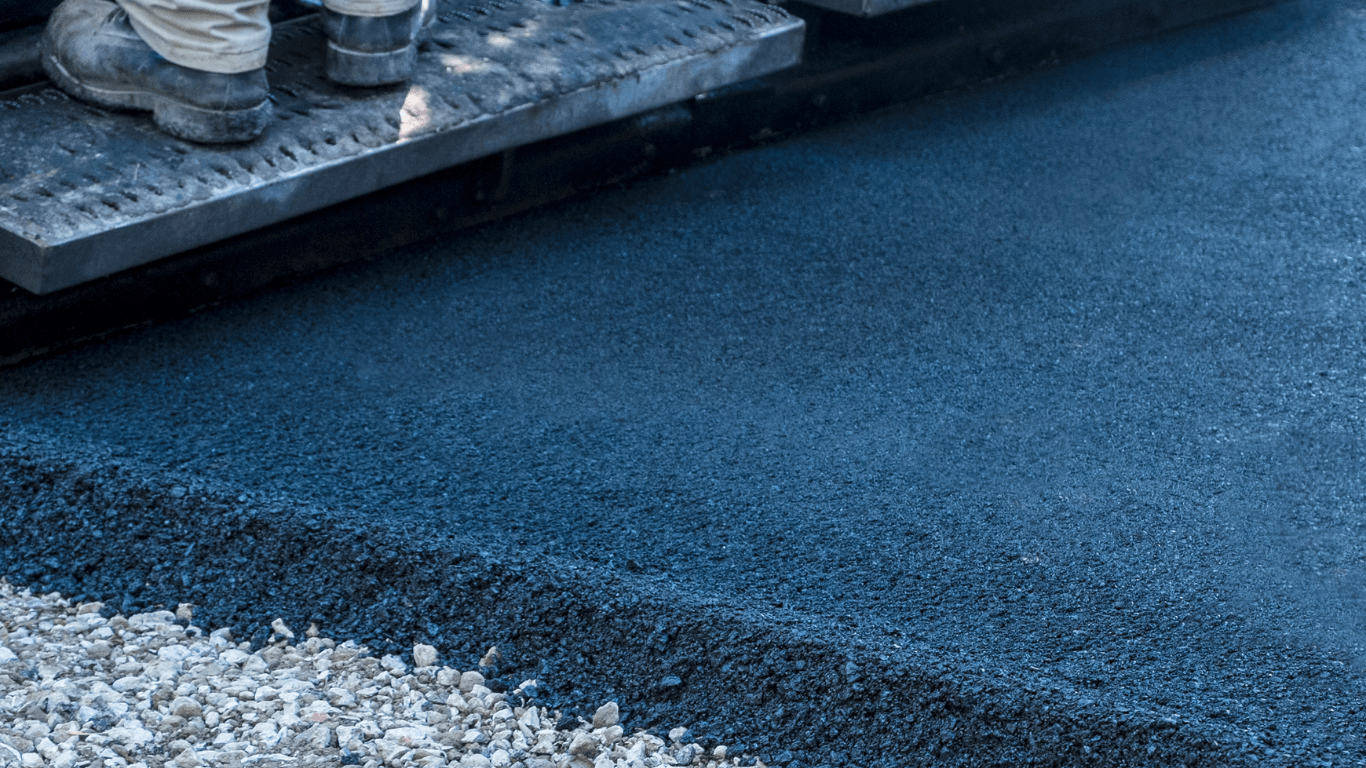 Close-up of freshly laid asphalt with a clean edge next to gravel, showing smooth compaction during an asphalt paving service in Arvada, CO