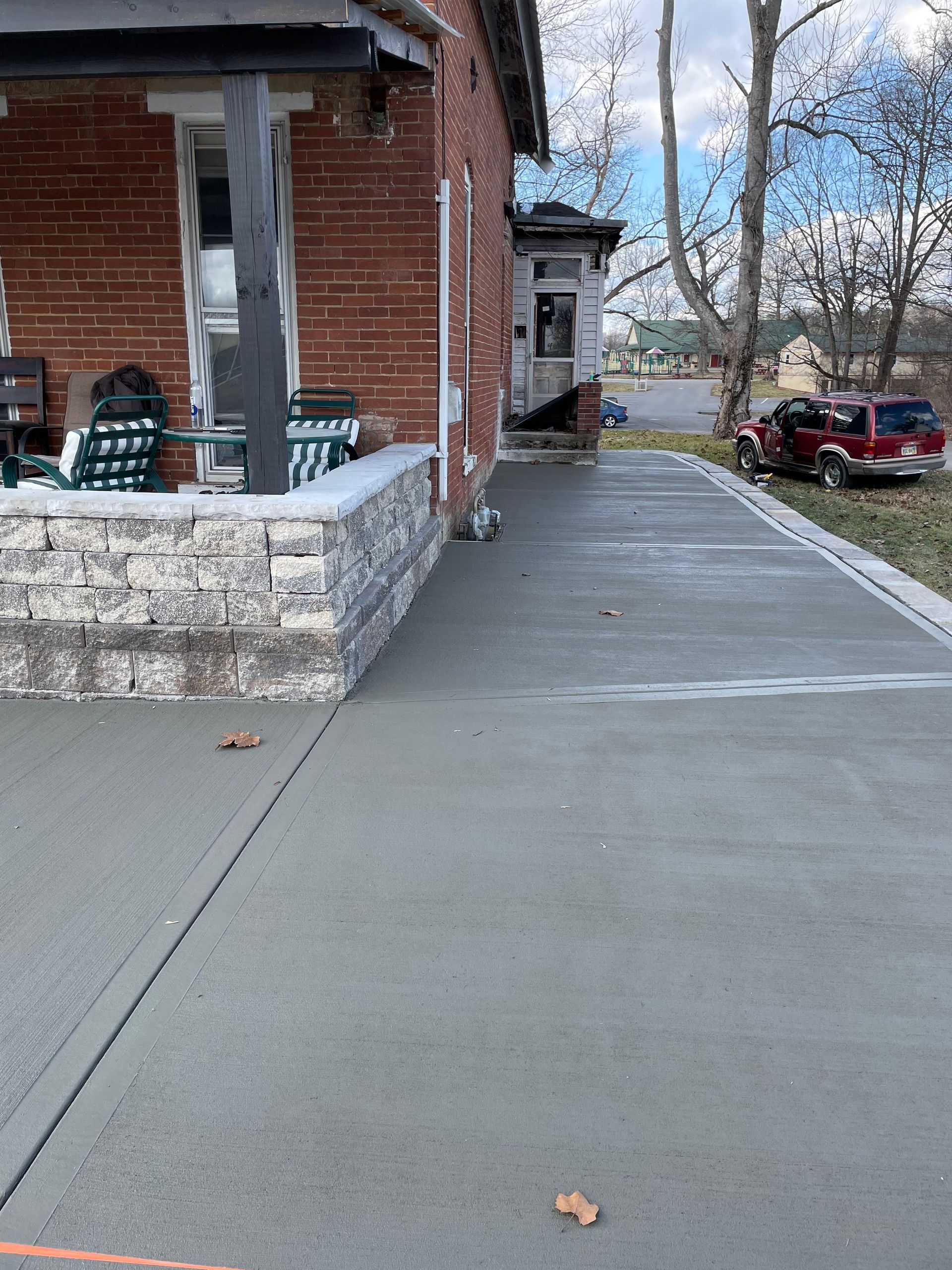 A brick house with a concrete driveway in front of it.