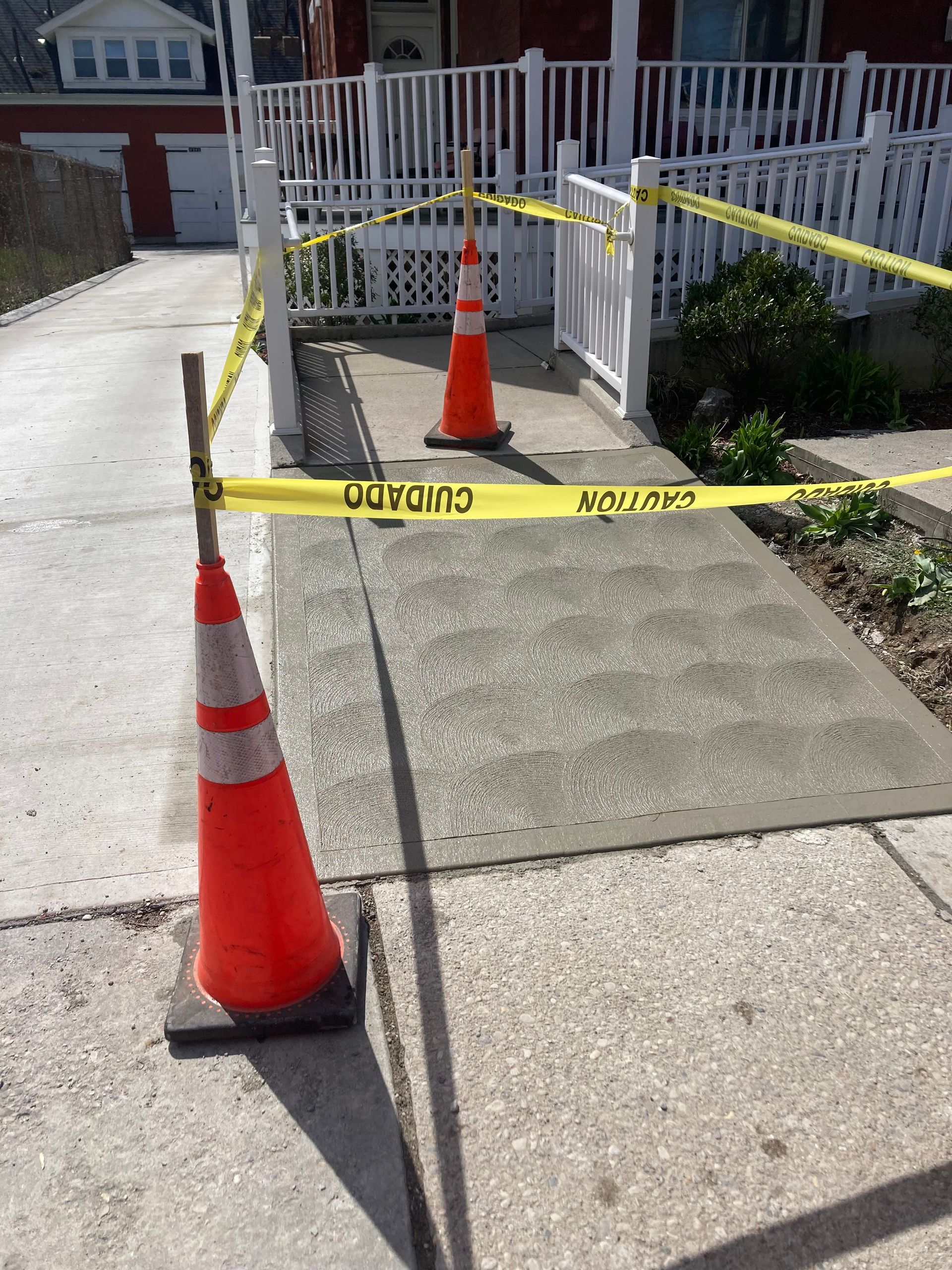 A yellow caution tape surrounds a sidewalk with orange cones