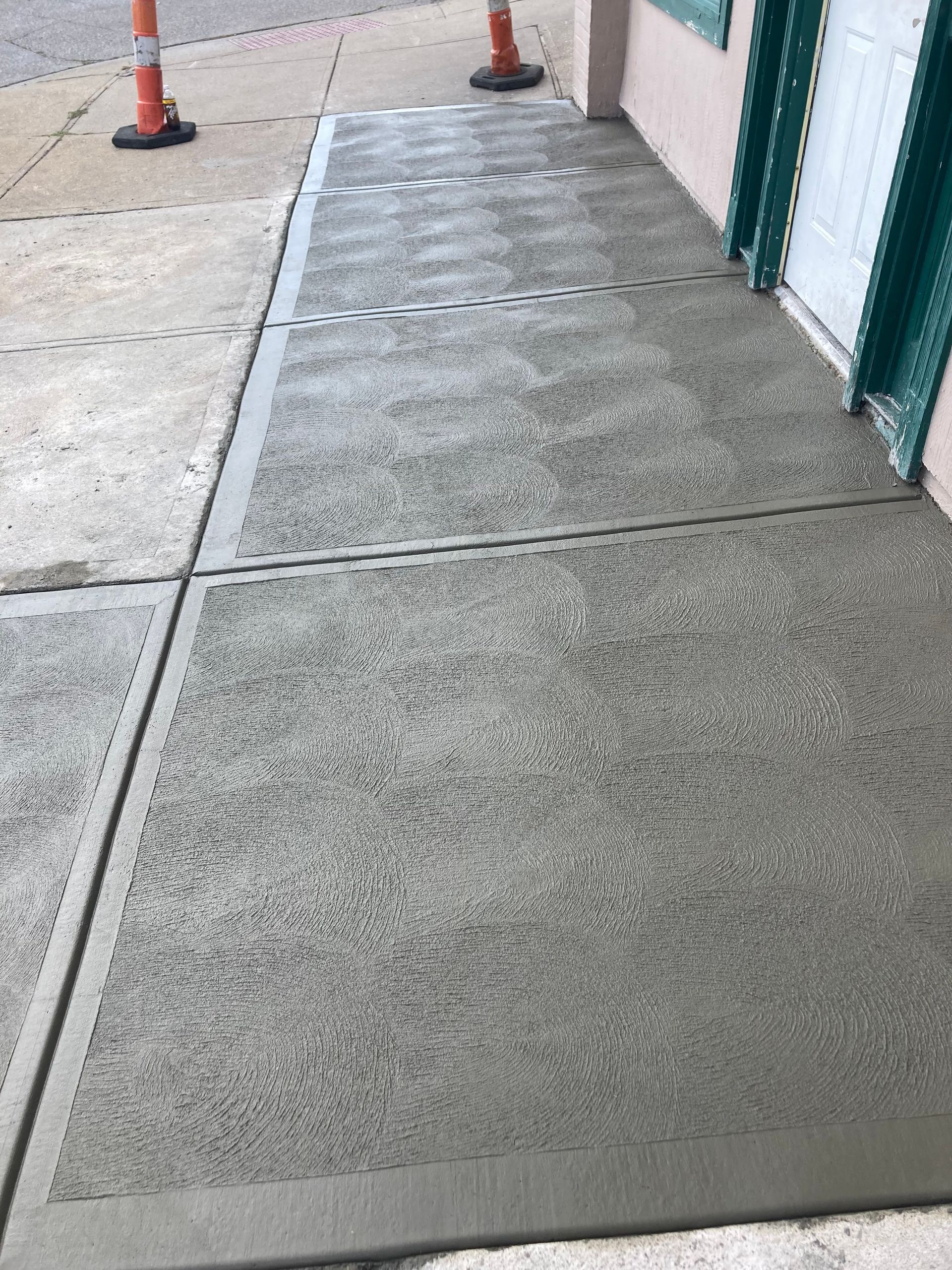 A concrete sidewalk is being built in front of a building.