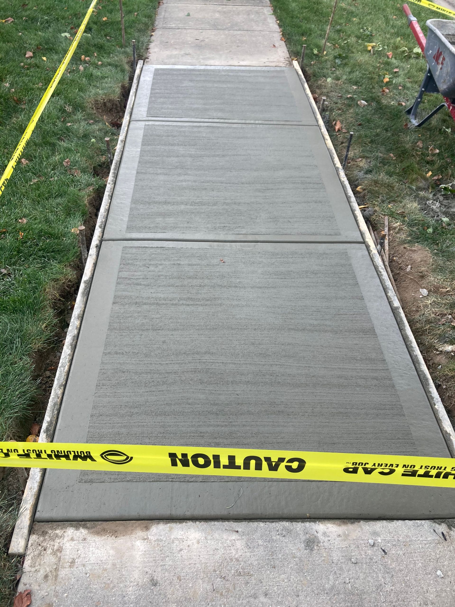 A concrete sidewalk with a yellow caution tape on it.