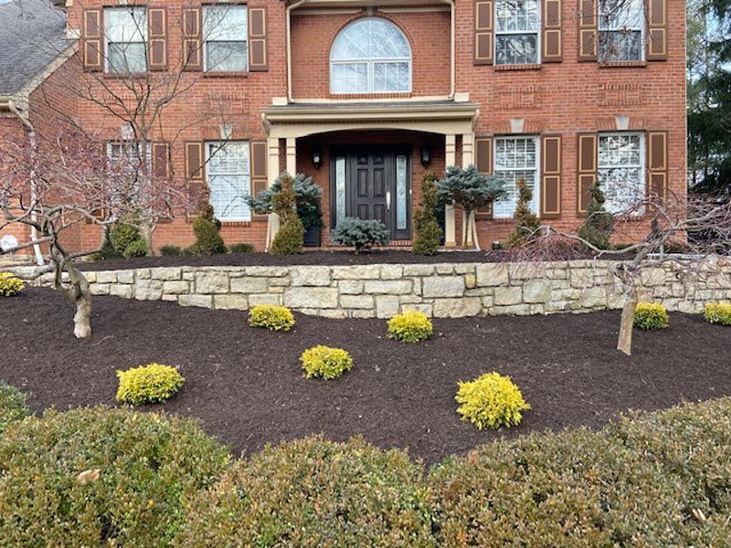 A large brick house with a stone wall in front of it