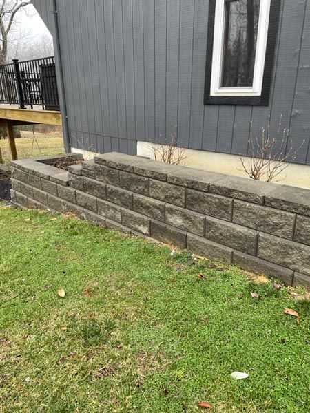 A stone wall is sitting in the grass in front of a house.
