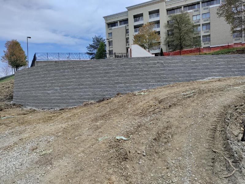 A large brick wall is being built on top of a dirt hill in front of a building.