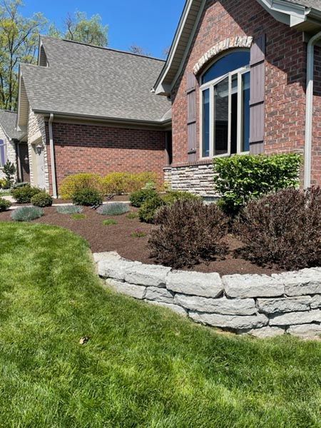 A brick house with a stone wall in front of it.